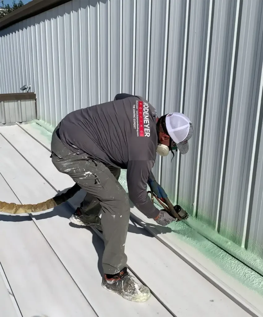 employee applying protective foam to roof